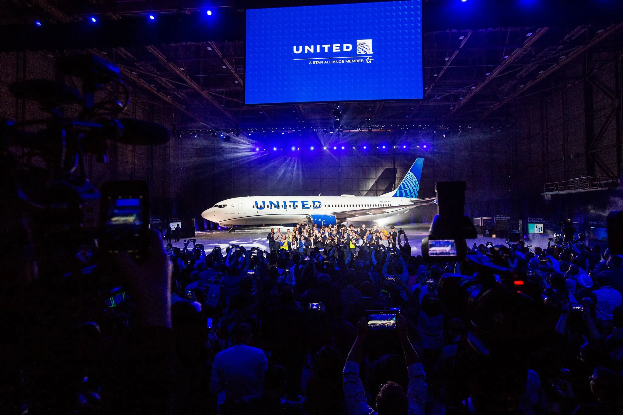Hundreds of people in an aircraft hanger for the launch of the United Airlines livery, with a United aircraft