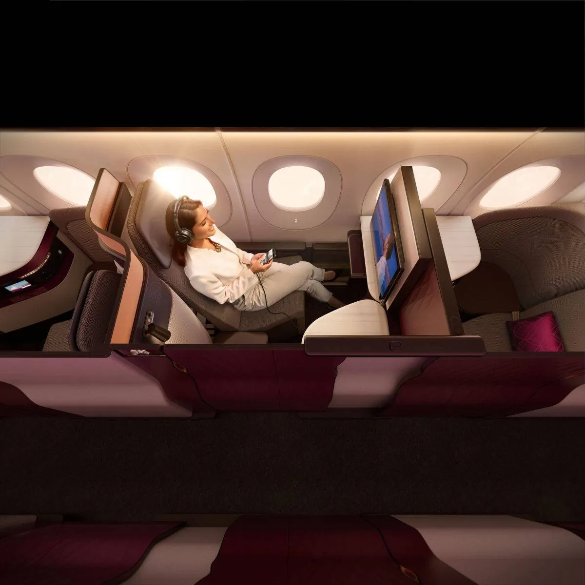 A woman watches TV seated in the privacy of an enclosed QSuite Business Class seat