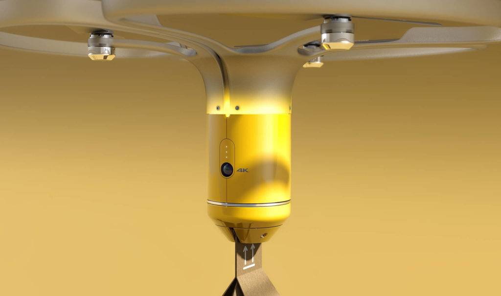 Close up view of a drone carrying a parcel, against a yellow backdrop