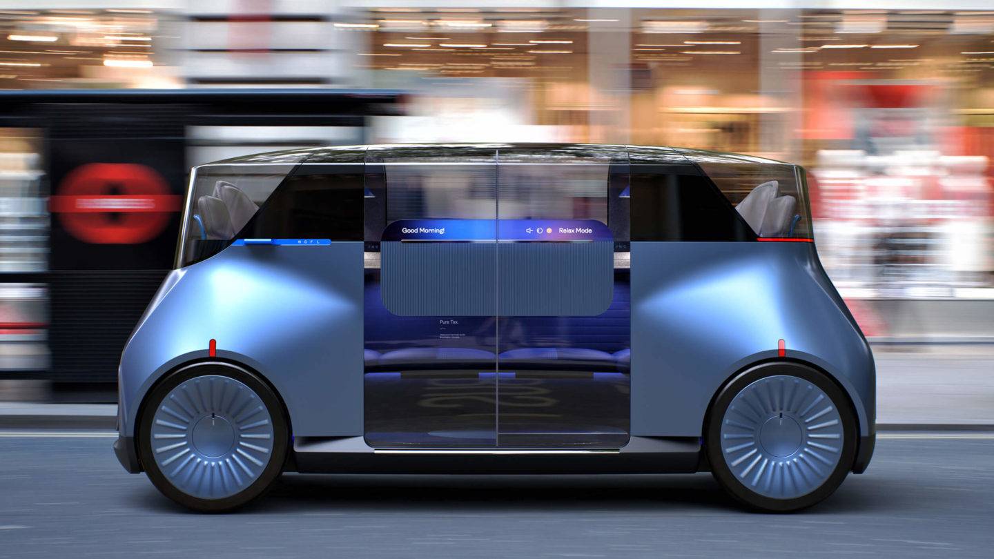 Side view of the New Car for London autonomous vehicle on a street, a bus stop and shop windows are seen in the background