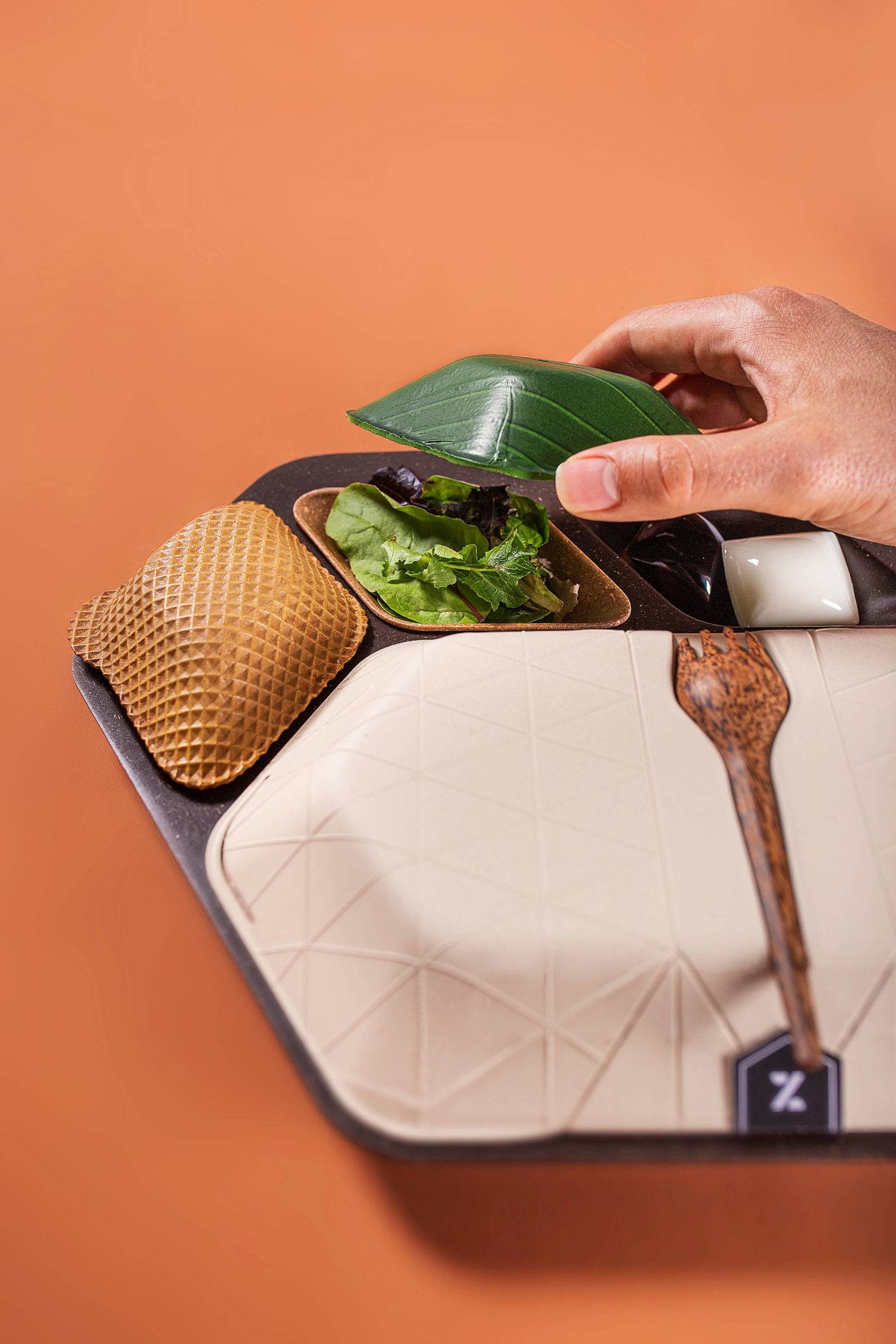 An airline mealtray made of sustainable materials, including wafer biscuit, banana leaf, coffee grounds and coconut wood