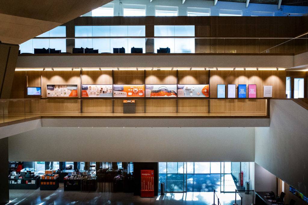 Exhibition view of Get Onboard at the Design Museum, with display cases on the wall seen from across a vast atrium