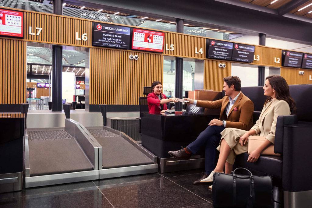 Two passengers seated on a large sofa at Business Class check in for Turkish Airlines at New Istanbul Airport