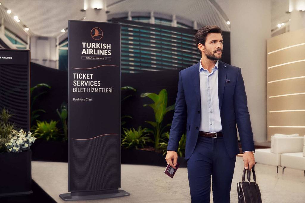 Man standing in front of wayfinding sign showing Turkish Airlines Ticket Services