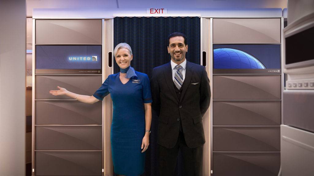 Two cabin crew standing in front of the United brand panels at the entrance of an aircraft