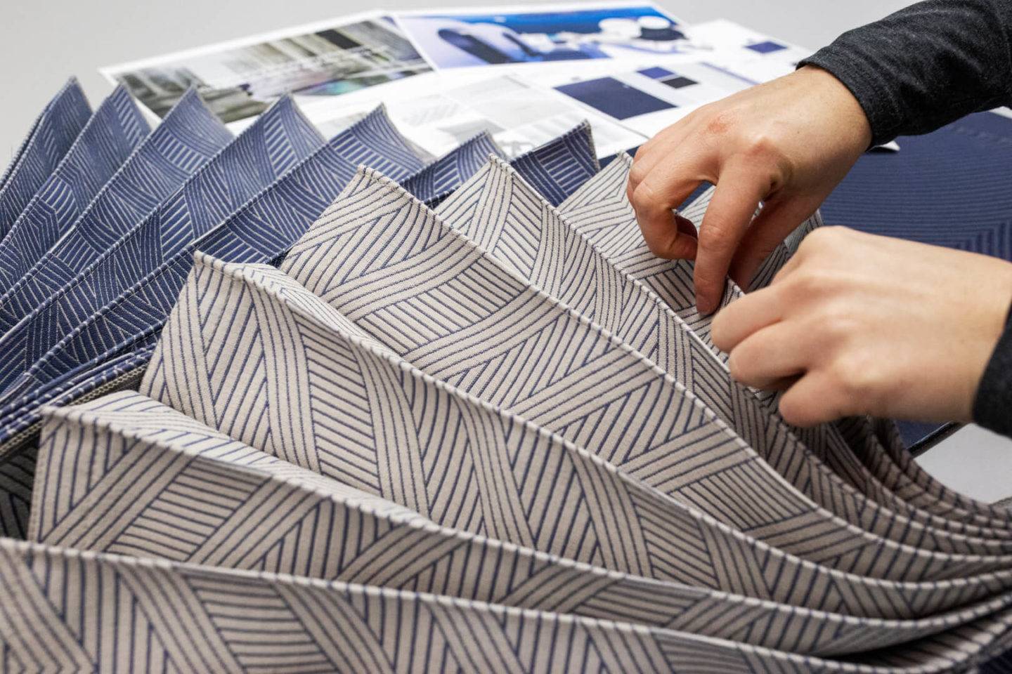 Two hands holding a sample of material of the new curtain on Aegean Airlines Neo aircraft