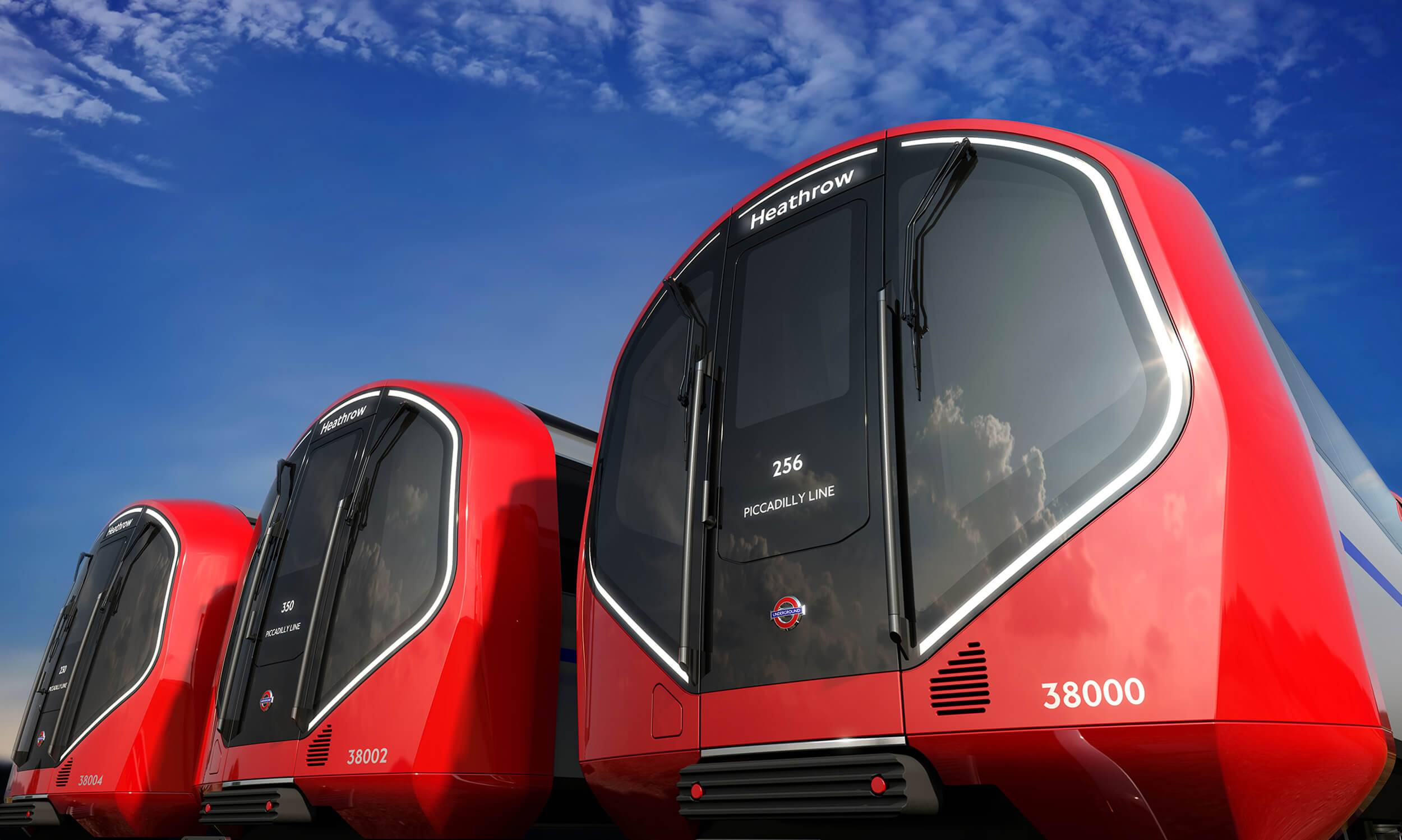 The front of three London Underground train carriages shown in daytime, with a blue sky above