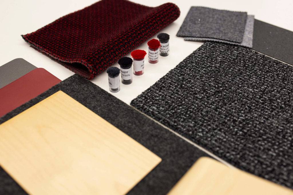 A selection of material samples in dark greys, light wood and red