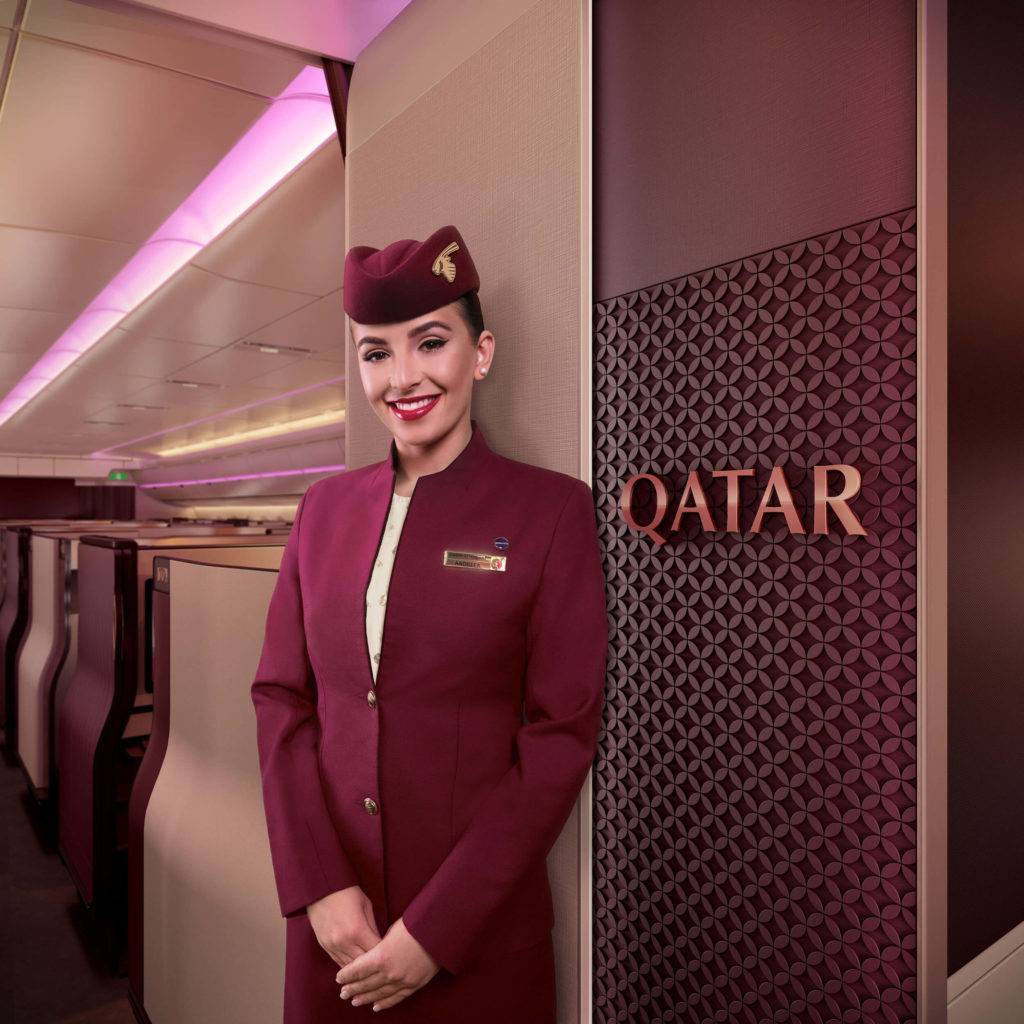Cabin crew stands next to a branded entrance panel