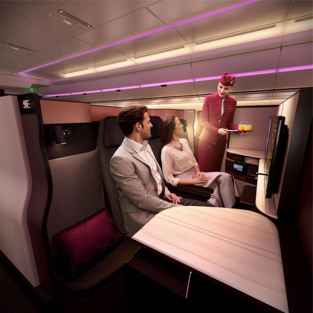 Cabin crew serves drinks to passengers in the Qatar Airways QSuite Business Class cabin