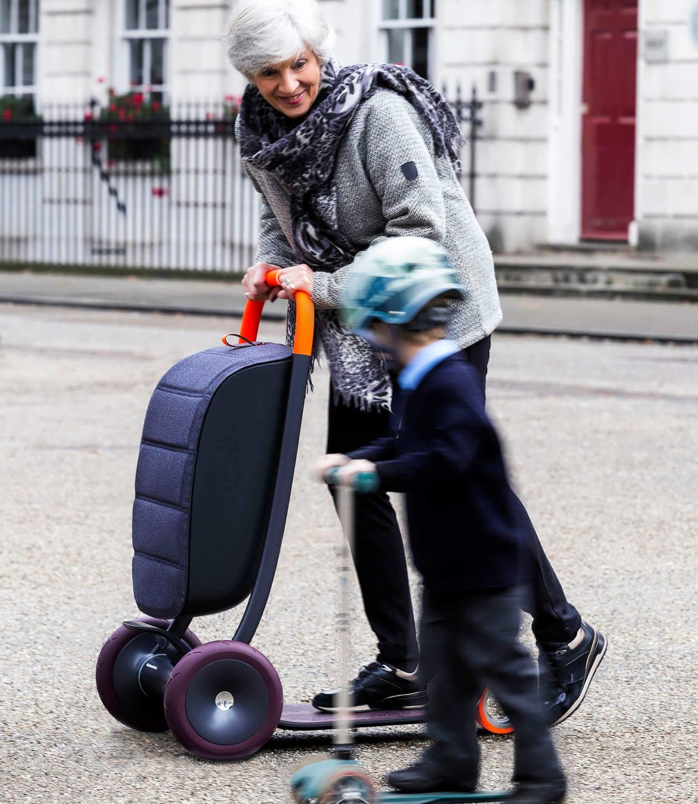 An older woman and a young boy are both riding a personal scooter