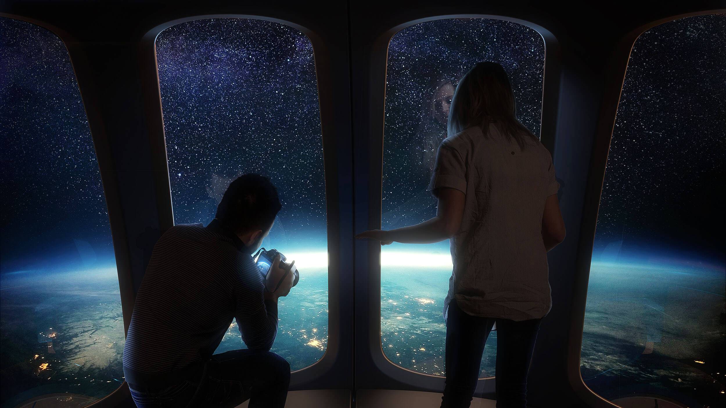 Two people inside a space capsule gazing at space and at the Earth beneath them. One of them is taking photos