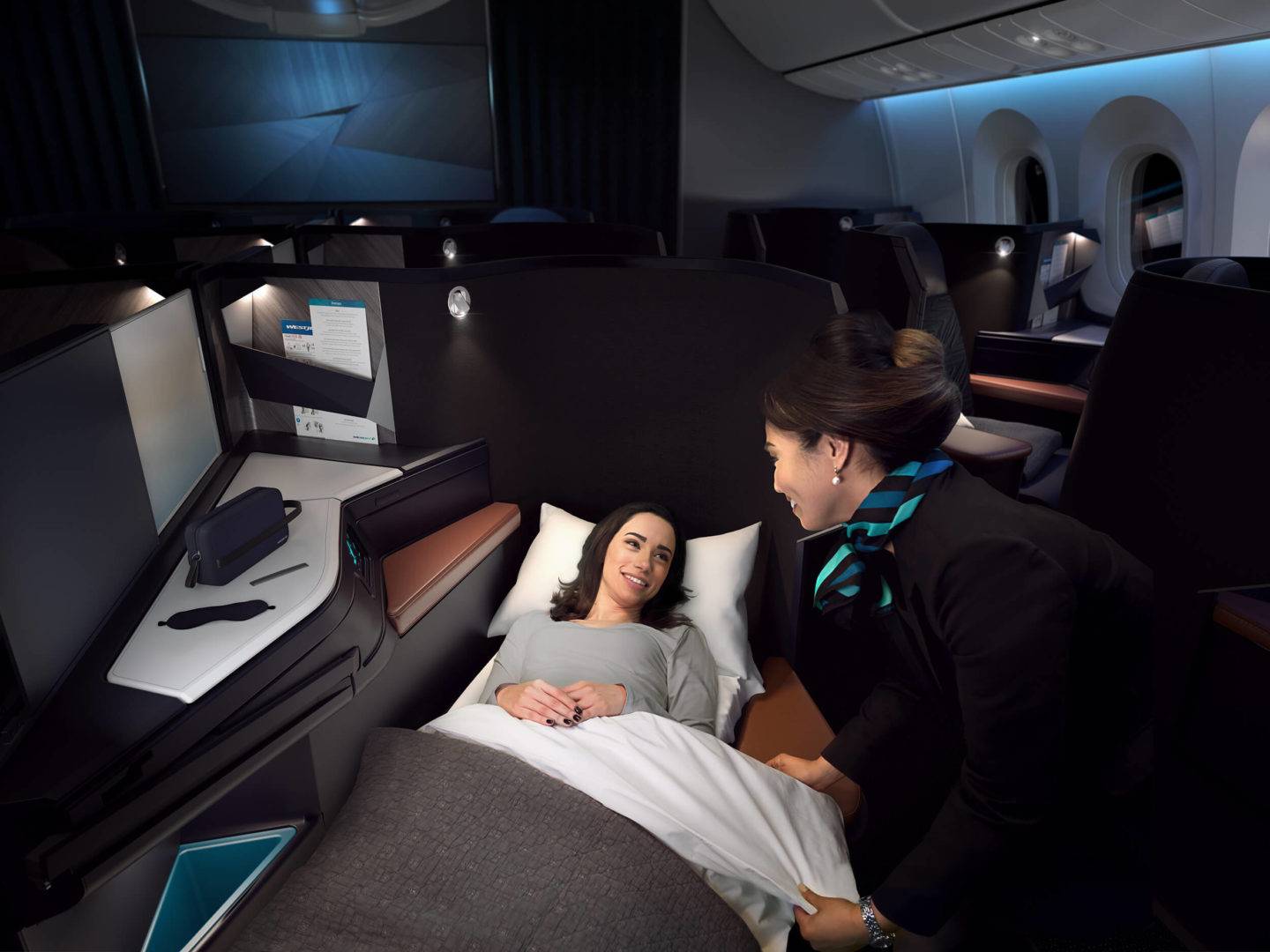 A passenger speaks to cabin crew while reclining in the WestJet Business Class seat in bed mode