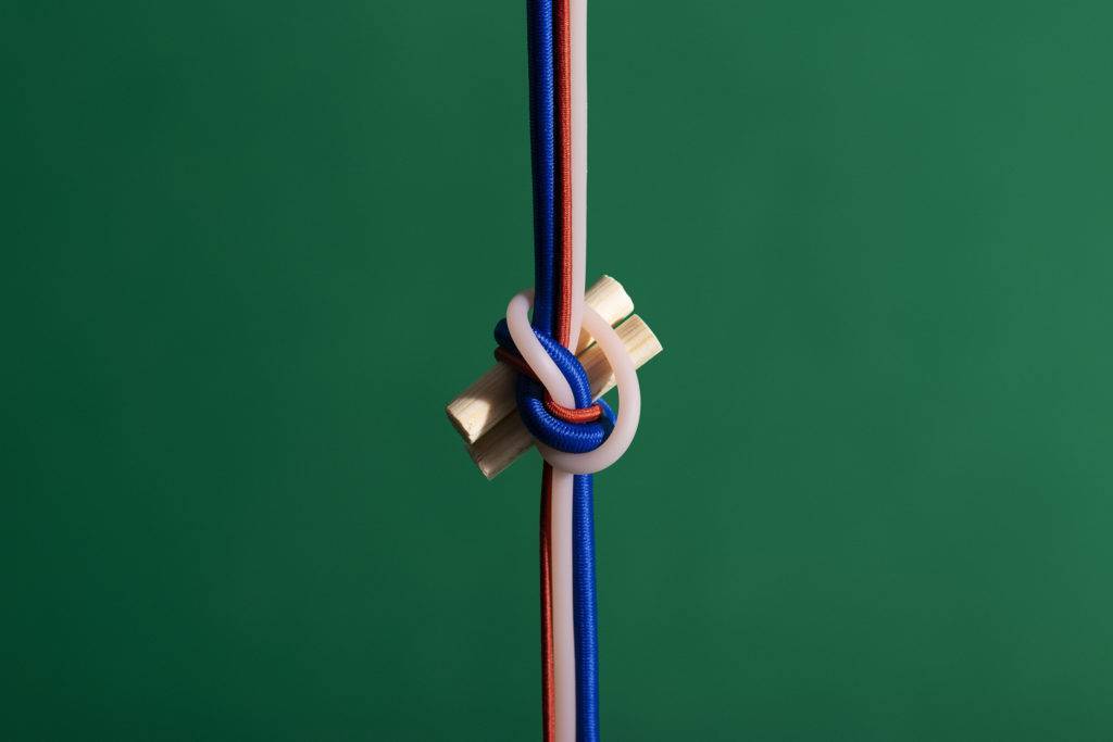 A knot made from different lengths of a rubber material against a dark green background