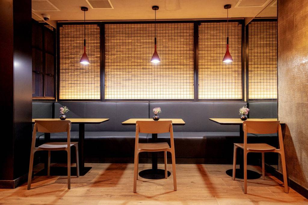 Three empty tables in a restaurant, with chairs and bench seating