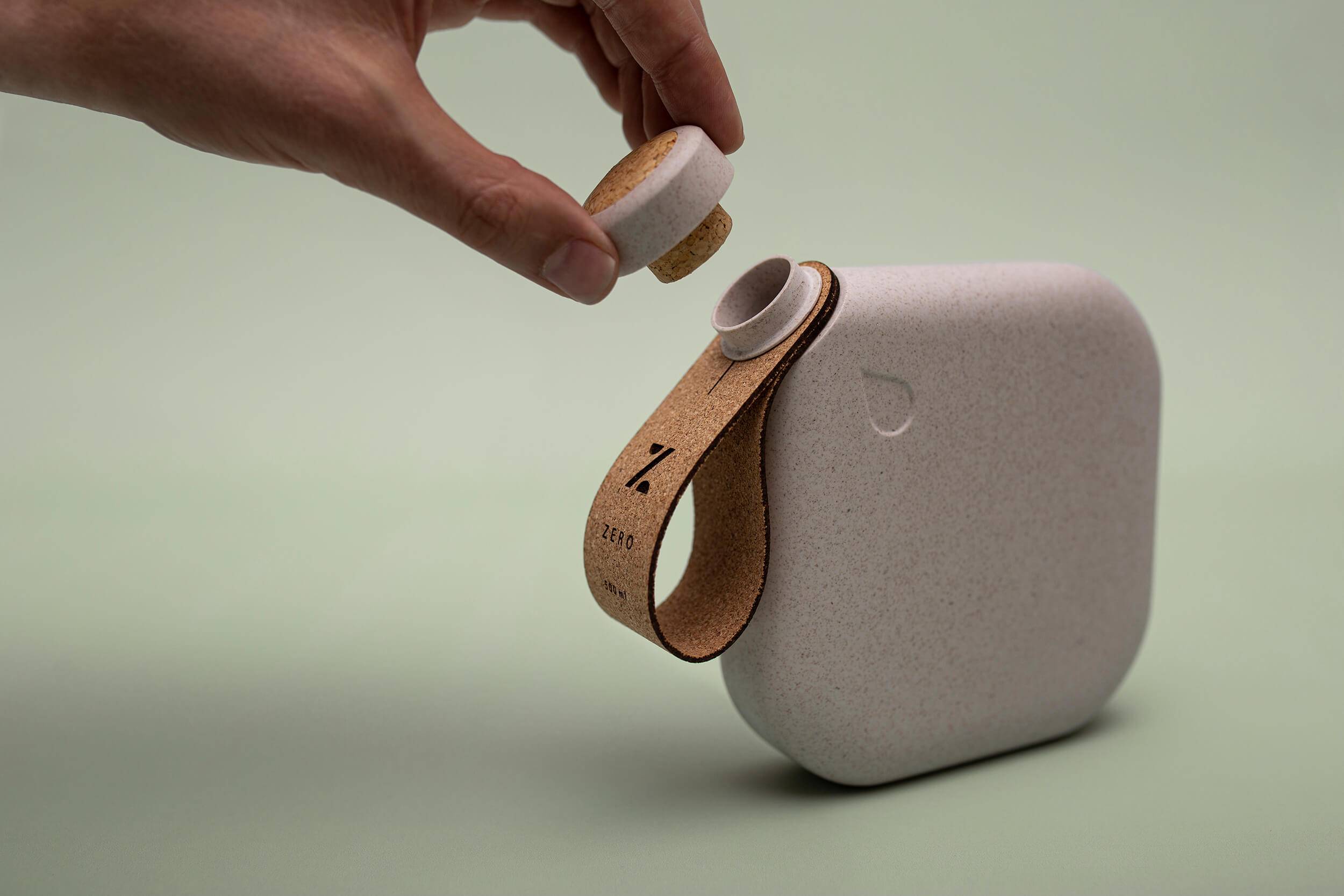 A hand uncorking a reusable water bottle made from sustainable materials
