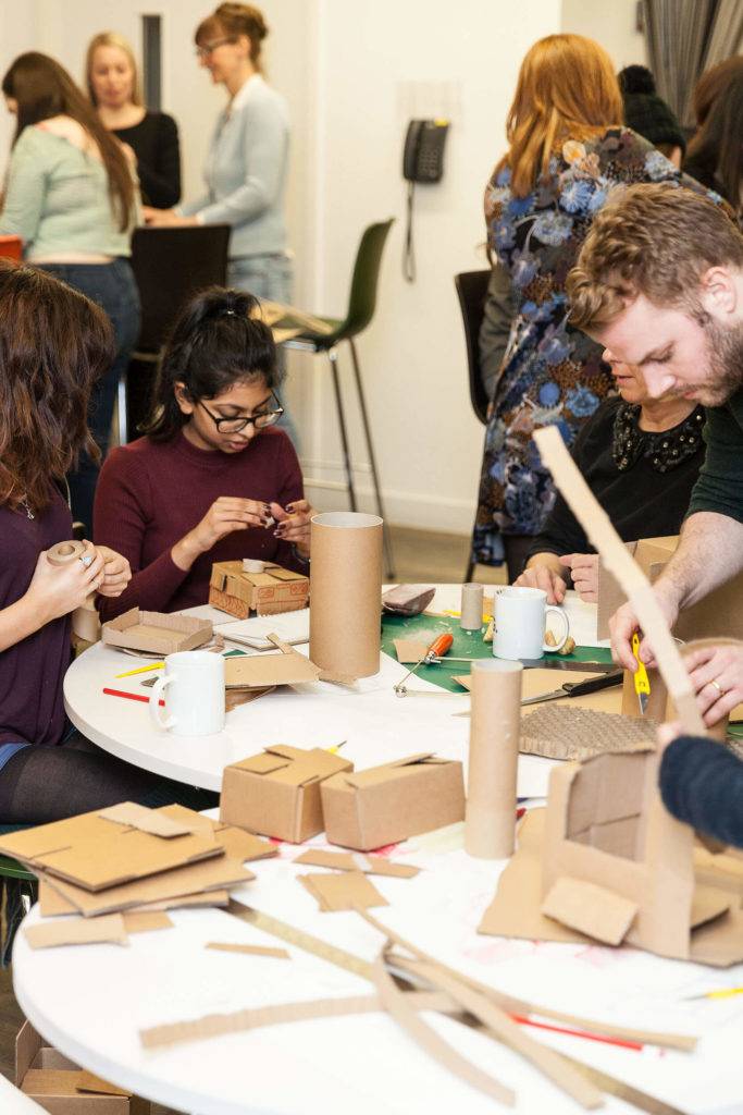 A group of young people in a workshop making cardboard models