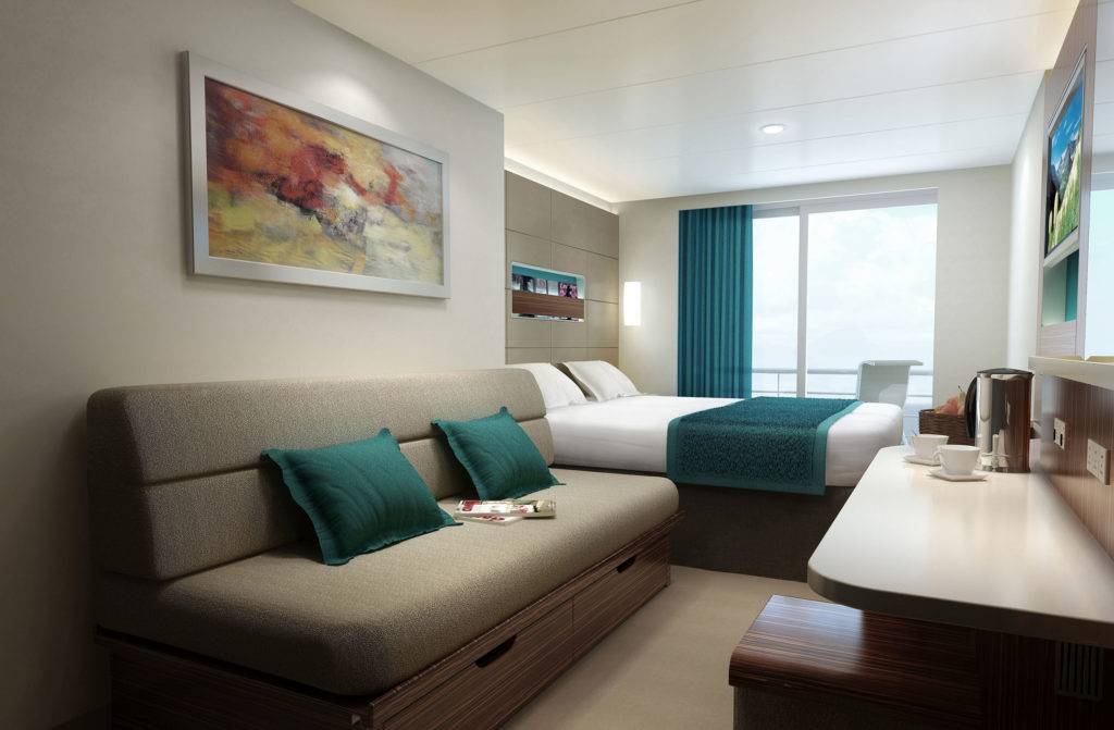 A contemporary stateroom with large double bed, a lounge area with a sofa, and large floor to ceiling windows