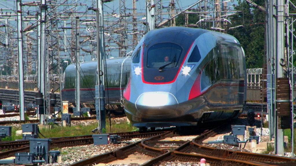 Front view of a train on tracks, with wiring seen above
