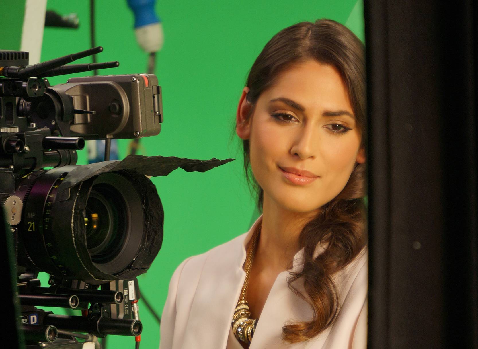 Woman at a film shoot in front of a camera with a green screen background