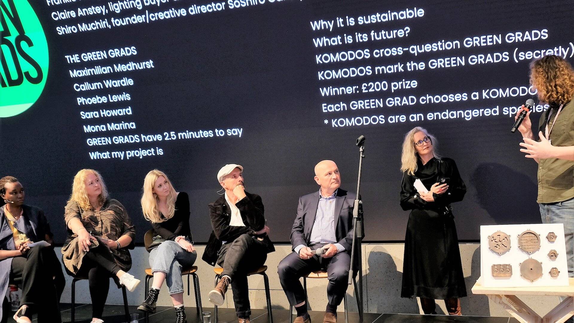 A panel of judges sits on a stage