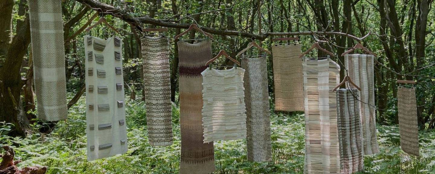 Textiles made from natural fibres hanging off a branch in the forest