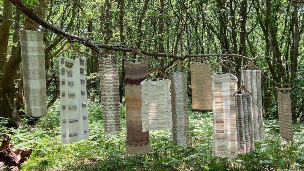 Textiles made from natural fibres hanging off a branch in the forest