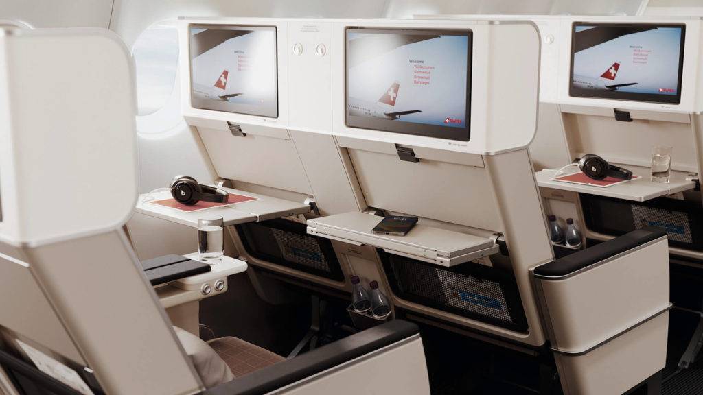 SWISS Premium Economy seats with tray tables down and showing screens